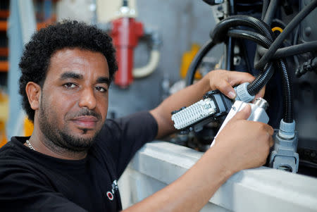 FILE PHOTO: Merhawi Tesfay, an immigrant from Eritrea poses during a Reuters interview at German plant engineering firm Kremer Machine Systems where he found a job as electrician and plant manufacturer in Gescher near Muenster, Germany, August 4, 2017. REUTERS/Wolfgang Rattay/File Photo