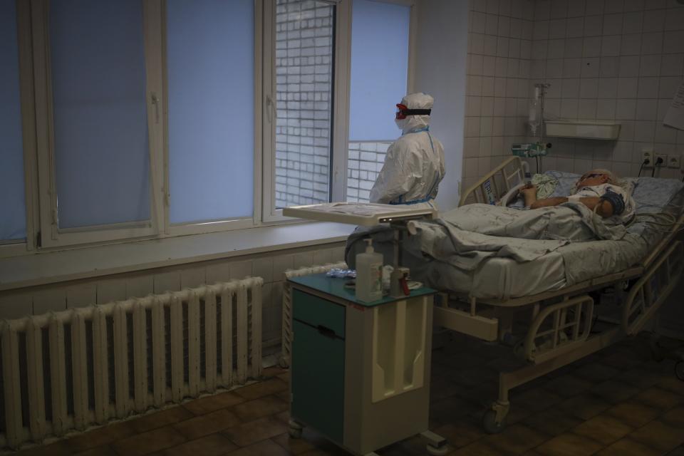 A medical staff member stands next to a patient with COVID-19 at an ICU of an hospital in Krasnodar, southern Russia, Thursday, Jan. 27, 2022. Russia has confirmed 11,404,617 cases of coronavirus and 328,770 deaths, according to the national coronavirus information center. Russia's total excess fatality count since the start of the coronavirus pandemic is at least 929,000. Under half the population is fully vaccinated. (AP Photo/Vitaliy Timkiv)