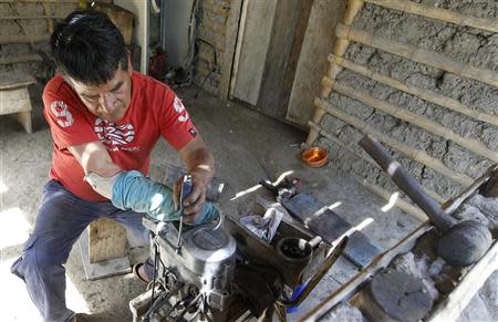 Manuel Bonilla, 62, who lost his right arm when rebels detonated a bus bomb in Toribio's central square, works on a motorcycle engine during a Reuters interview in Toribio February 6, 2014. REUTERS/Jaime Saldarriaga