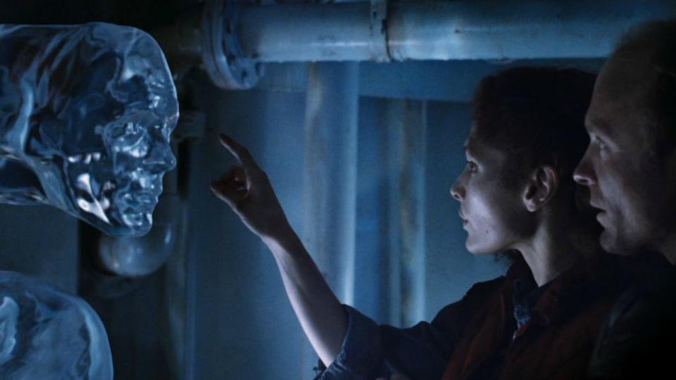 a woman reaches out a hand to touch a human head made of water