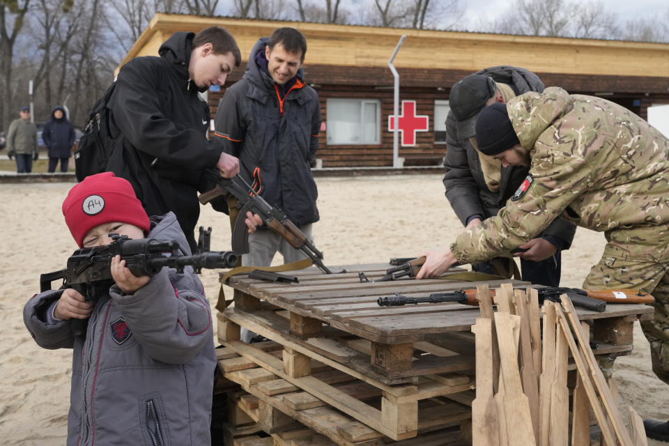 A boy plays with a weapon as an instructor shows a Kalashnikov assault rifle while training members of a Ukrainian far-right group train, in Kyiv, Ukraine, Sunday, Feb. 20, 2022. Russia extended military drills near Ukraine's northern borders Sunday amid increased fears that two days of sustained shelling along the contact line between soldiers and Russia-backed separatists in eastern Ukraine could spark an invasion. (AP Photo/Efrem Lukatsky)