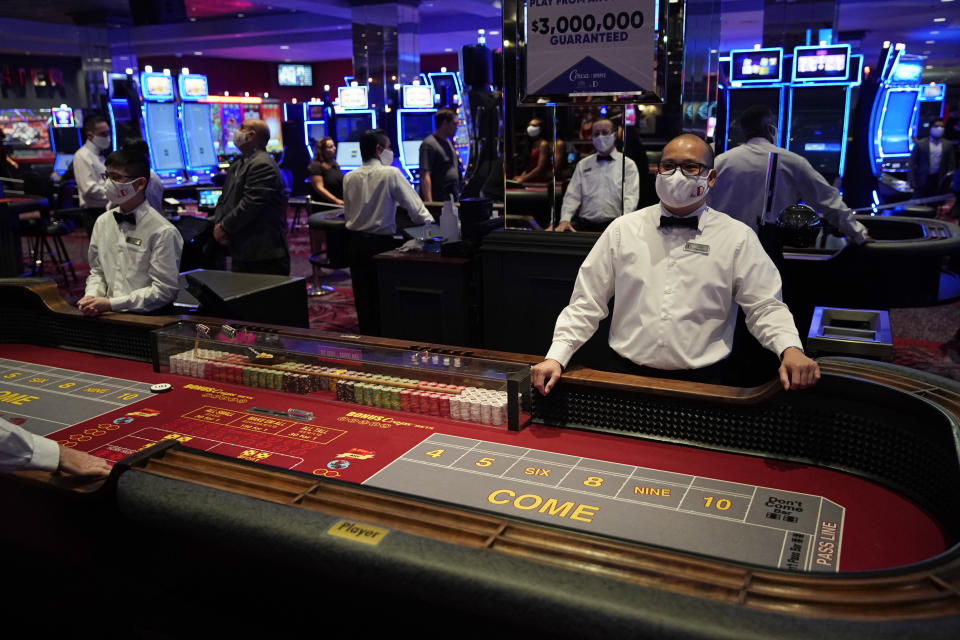 FILE - Dealers in masks wait for customers before the reopening of the D Las Vegas hotel and casino in Las Vegas, in this Wednesday, June 3, 2020, file photo. Governments and businesses are scrambling to change course following new federal guidance calling for the return of mask wearing in virus hot spots amid a dramatic spike in COVID-19 cases and hospitalizations nationwide. Nevada and Kansas City were among the locations that moved swiftly to re-impose indoor mask mandates following Tuesday’s announcement from the Centers for Disease Control and Prevention. (AP Photo/John Locher, FIle)