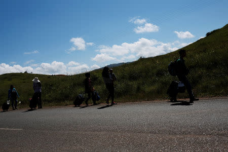 Venezuelans walk along a road towards the Brazilian border after being expelled from the Pacaraima border control point by Brazilian civilians, in Santa Elena, Venezuela August 19, 2018. REUTERS/Nacho Doce