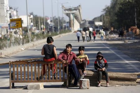 Children sit on a road blockade by the demonstrators from the Jat community to block the Delhi-Haryana national highway during a protest at Sankhol village in Haryana, February 21, 2016. REUTERS/Adnan Abidi