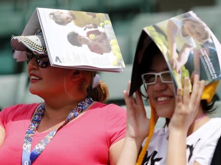 Fans sheild themselves from the sun using programmes at the Wimbledon Tennis Championships in London, July 1, 2015. REUTERS/Suzanne Plunkett
