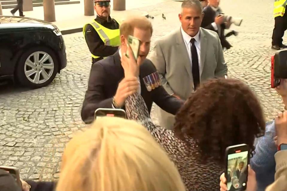 Prince Harry (center) grabbed a woman’s arm during his trip home to London. Reuters