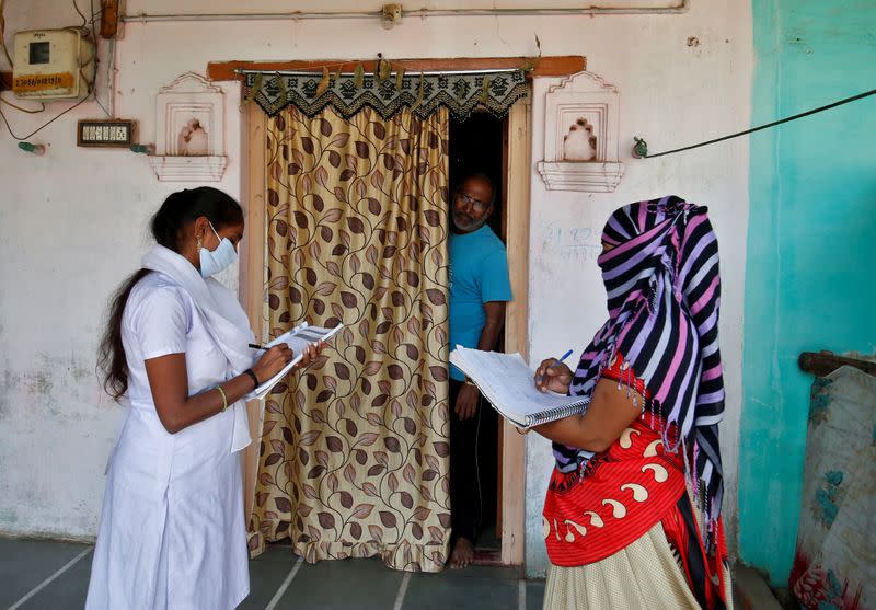 FILE PHOTO: Health workers collect personal data from a man as they prepare a list during a door-to-door survey on the outskirts of Ahmedabad