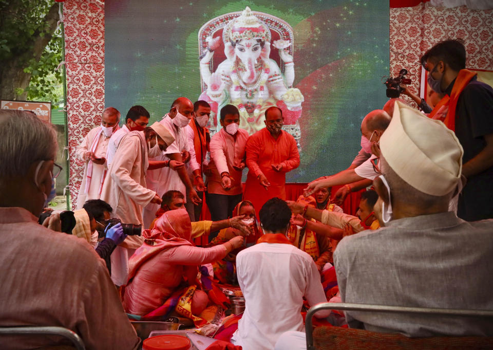 Hindus offer prayers for a groundbreaking ceremony of a temple dedicated to the Hindu god Ram in Ayodhya, at the Vishwa Hindu Parishad, or World Hindu Council, headquarters in New Delhi, India, Wednesday, Aug. 5, 2020. The coronavirus is restricting a large crowd, but Hindus were joyful before Prime Minister Narendra Modi breaks ground Wednesday on a long-awaited temple of their most revered god Ram at the site of a demolished 16th century mosque in northern India. (AP Photo/Manish Swarup)