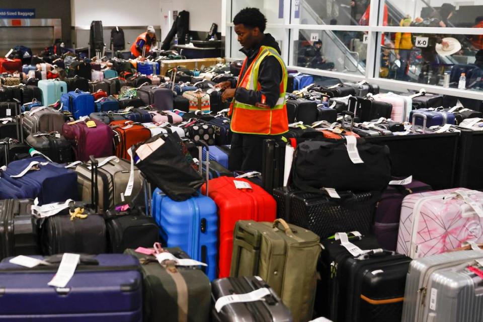 Un empleado del aeropuerto organiza las cientos de maletas de los pasajeros cuyos vuelos fueron cancelados o retrasados, en el Aeropuerto Internacional de Oakland, California, el martes 27 de diciembre de 2022. (Jessica Christian/San Francisco Chronicle via AP)