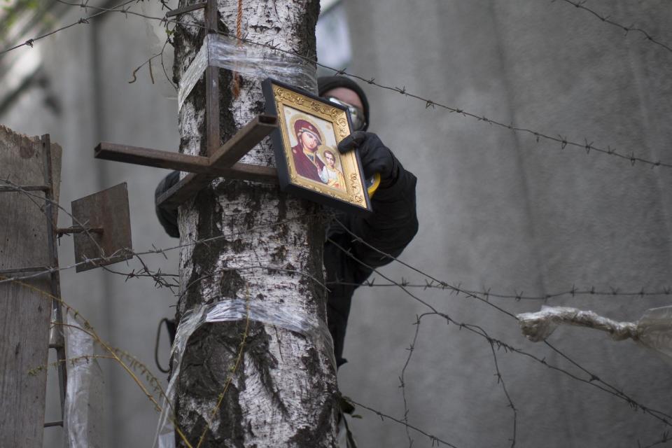 Un activista prorruso coloca una imagen de la Trinidad Ortodoxa en las barricadas afuera de las oficinas de gobierno en Slovyansk, Ucrania, el sábado 19 de abril de 2014. Las fuerzas prorrusas se preparaban para celebrar la Pascua Ortodoxa en las barricadas en aproximadamente una decena de ciudades, pese a un acuerdo internacional de desarme y de liberación de las instalaciones. (Foto AP/Alexander Zemlianichenko)