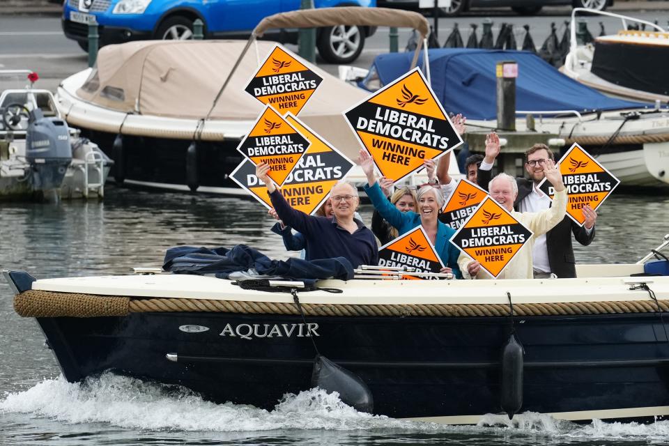 A boat of Liberal Democrat supporters passes by as Rishi Sunak visits Leander Rowing Club (POOL/AFP via Getty Images)