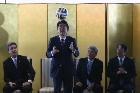 Japan's Prime Minister Shinzo Abe heads the ball during a meeting with Brazilian soccer players in Brasilia, August 1, 2014. REUTERS/Ueslei Marcelino