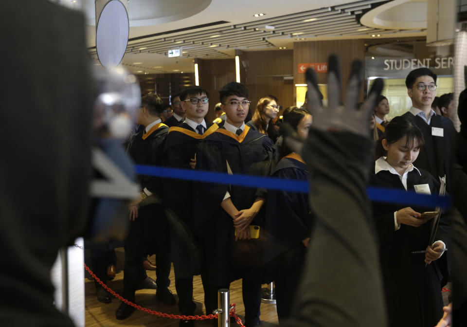 A protester stands outside a holding room for graduates during an anti-government rally that briefly disrupts a graduation ceremony at Hong Kong University of Science and Technology in Hong Kong, Thursday, Nov. 7, 2019. (AP Photo/Dita Alangkara)