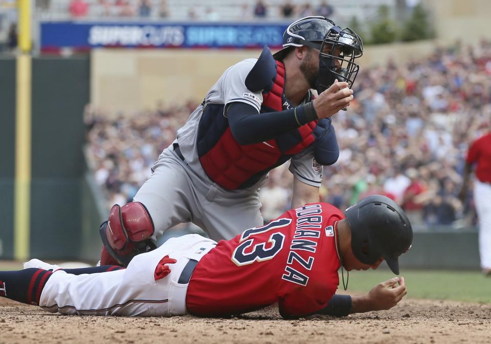 Cleveland Indians catcher Kevin Plawecki, left, tags out Minnesota Twins' Ehire Adrianza, right, as he tried to score from first base on a double by Marwin Gonzalez in the ninth inning of a baseball game Sunday, Aug. 11, 2019, in Minneapolis. The Indians won 7-3 in 10 innings. (AP Photo/Jim Mone)