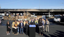 California Gov. Gavin Newsom, center,, speaks during a news conference about repairs for a stretch of Interstate 10, Tuesday morning Nov. 14, 2023, in Los Angeles. It will take at least three weeks to repair the Los Angeles freeway damaged in an arson fire, the Newsom said Tuesday, leaving the city already accustomed to soul-crushing traffic without part of a vital artery that serves hundreds of thousands of people daily. (Dean Musgrove/The Orange County Register via AP)