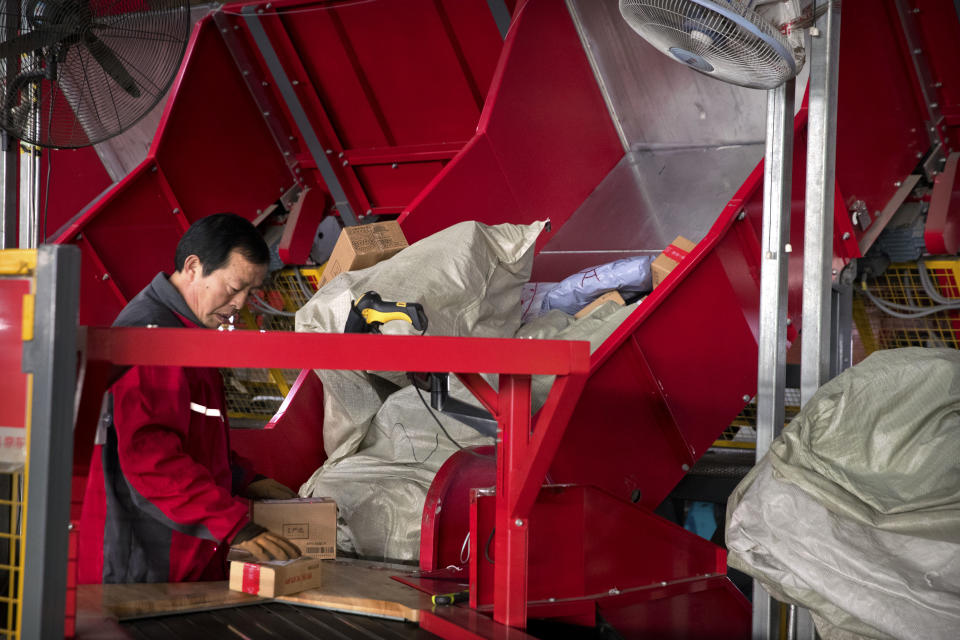 A worker places packages onto a conveyor belt in an automated parcel sorting facility for e-commerce retailer JD.com in Tongzhou, suburban Beijing, Sunday, Nov. 11, 2018. Online shoppers spent more than $14 billion within the first two hours of China's annual buying frenzy on Sunday, once again breaking records as the consumer tradition enters its 10th year. (AP Photo/Mark Schiefelbein)