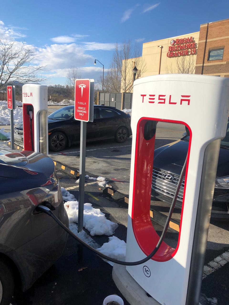 A Tesla takes a charge from a new charging station in Biltmore Park. Signs in the lot say the stations are for Tesla vehicle charging only.