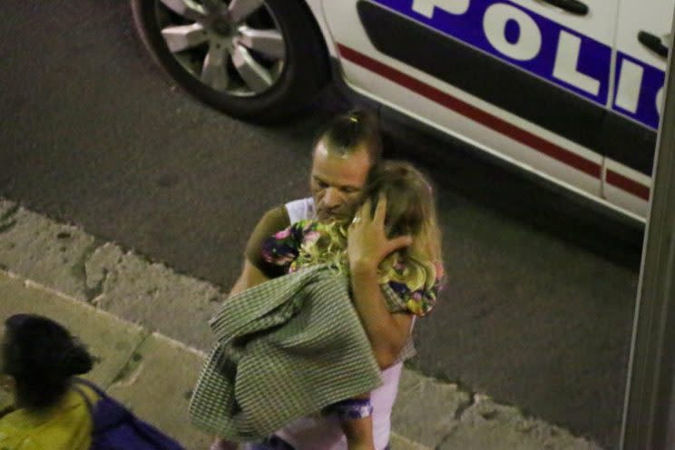 A man holds a child after a truck plowed through Bastille Day revelers in the French resort city of Nice, France, on Thursday. (Photo: Sasha Goldsmith/AP)