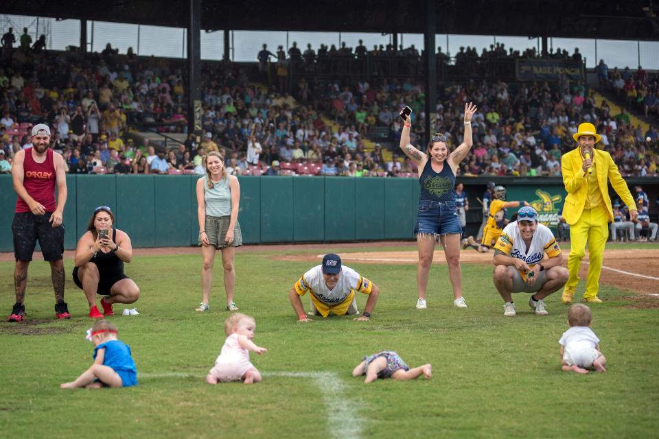 Four infants and their parents take part in what the Savannah Bananas call The Slowest Race, at the team's baseball game against the Wilmington Sharks, Saturday, June 11, 2022, in Savannah, Ga. (AP Photo/Stephen B. Morton)