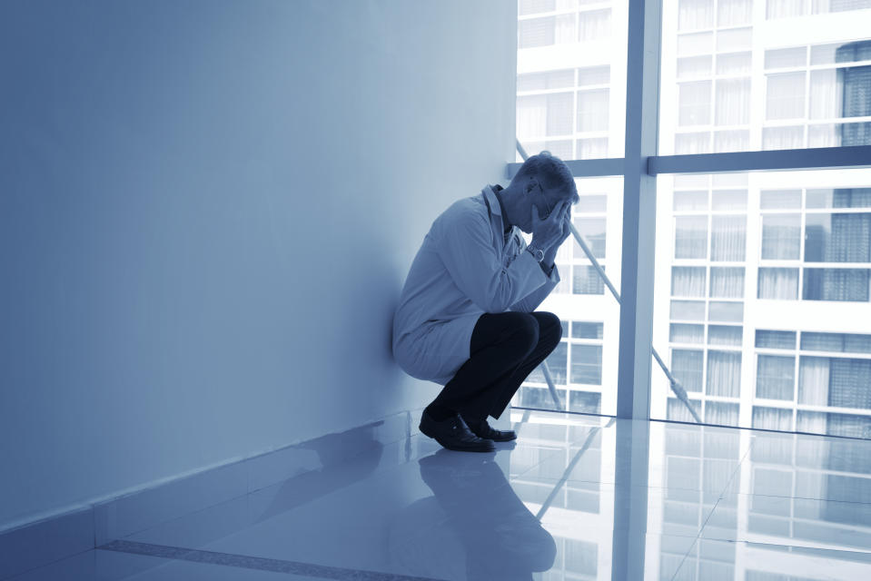 Doctor sitting in despair in hospital corridor