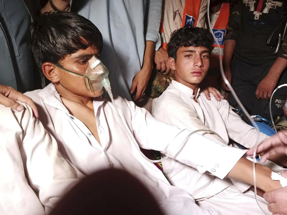 Youngsters, left, who were trapped in a broken cable car, receive first aid following their rescue, in Pashto village, a mountainous area of Battagram district in Pakistan's Khyber Pakhtunkhwa province, late Tuesday, Aug. 22, 2023. Army commandos using helicopters and a makeshift chairlift rescued eight people from a broken cable car dangling hundreds of meters (feet) above a canyon Tuesday in a remote part of Pakistan, authorities said. (AP Photo/Nasir Mahmood)