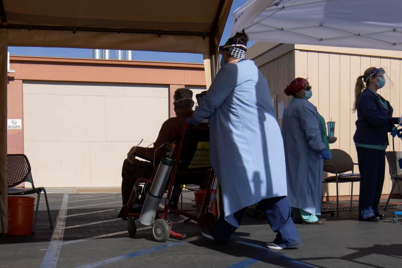 Healthcare workers attend to a patient as St. Mary Medical Center resorts to using triage tents outside in California