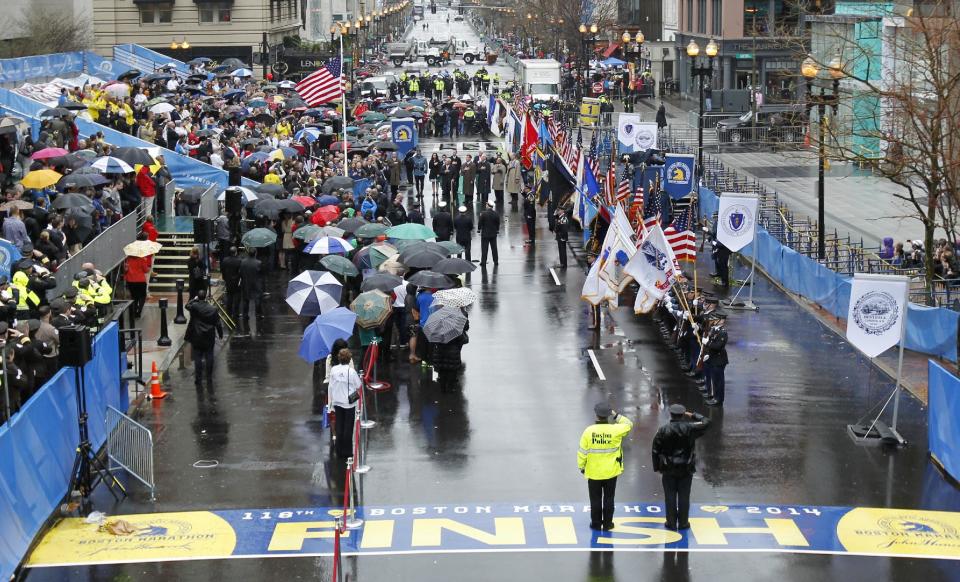 Survivors, officials, first responders and guests pause as the flag is raised at the finish line during a tribute in honor of the one year anniversary of the Boston Marathon bombings, Tuesday, April 15, 2014 in Boston. (AP Photo/Charles Krupa)