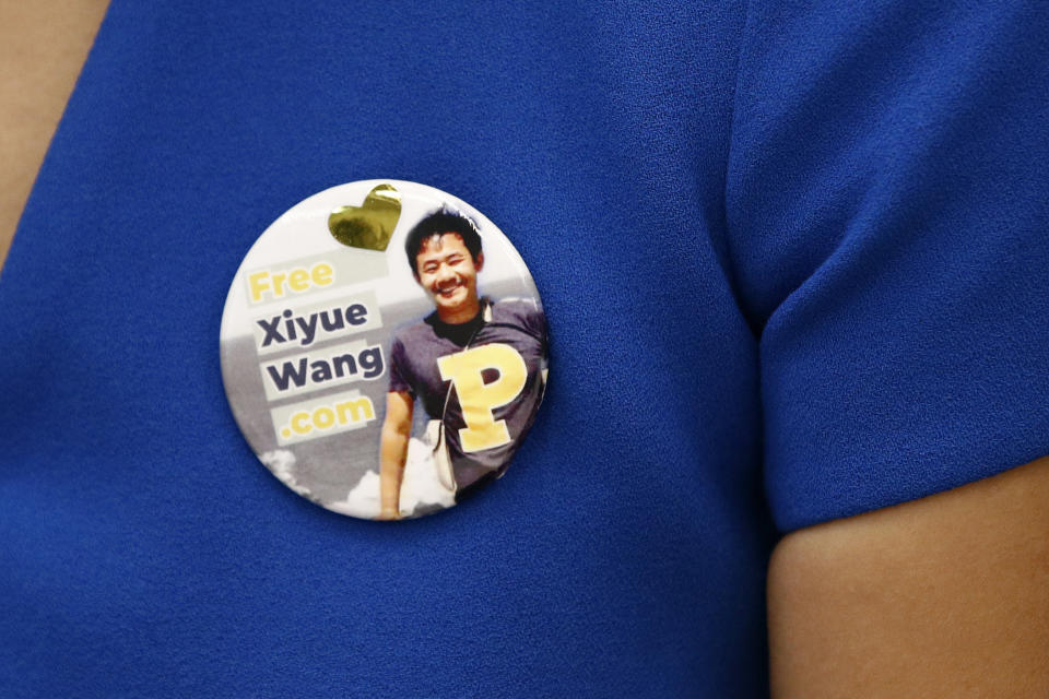 Hua Qu, the wife of Xiyue Wang, a Princeton University graduate student being held at an Iranian prison, wears a button bearing a picture of her husband as she speaks at a news conference to mark the third anniversary of his imprisonment, Thursday, Aug. 8, 2019, at the National Press Club in Washington. (AP Photo/Patrick Semansky)