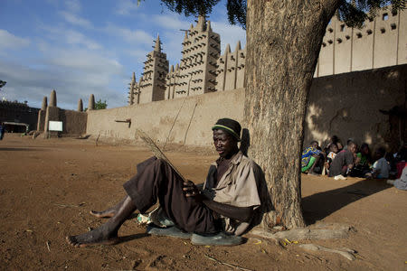 A man practices reciting Quranic verses handwritten on a piece of wood in front of the Grand Mosque of Djenne, Mali September 1, 2012. REUTERS/Joe Penney