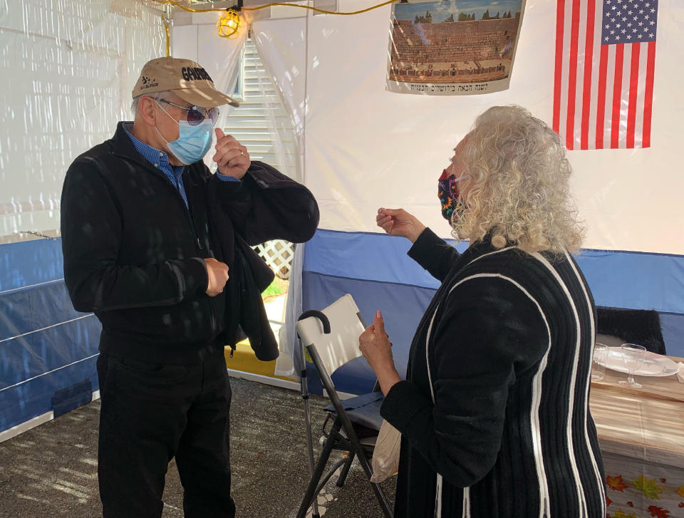 In this photo provided by Larry Brandspiegel, Holocaust survivors Israel "Sasha" Eisenberg, left, and Ruth Brandspiegel are reunited on Oct. 3, 2020, in East Brunswick, N.J. for the first time in more than 70 years since their families left the Hallein Displaced Persons Camp in Austria. They met under a sukkah, a temporary shelter used to celebrate the weeklong Jewish fall holiday of Sukkot. (Larry Brandspiegel via AP)