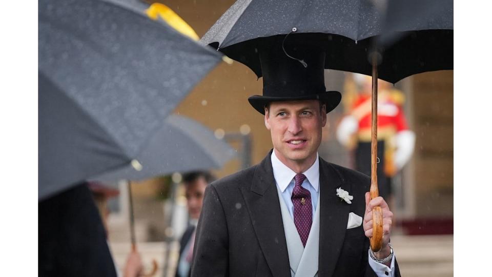 Britain's Prince William wearing top hat and sheltering under umbrella 