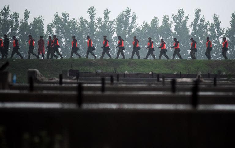 Chinese soldiers walk on a river bank near the unseen capsized passenger ship Dongfangzhixing or "Eastern Star" vessel which sank in the Yangtze river in Jianli on June 2, 2015