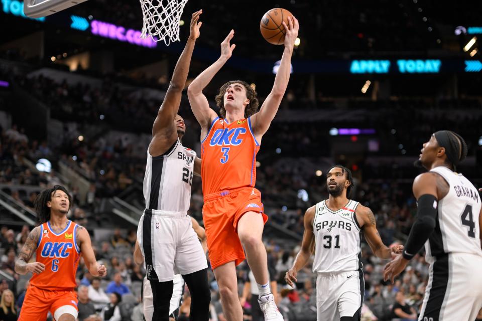 Oklahoma City Thunder's Josh Giddey (3) goes to the basket against San Antonio Spurs' Charles Bassey (28) during the first half of an NBA basketball game, Sunday, March 12, 2023, in San Antonio. (AP Photo/Darren Abate)
