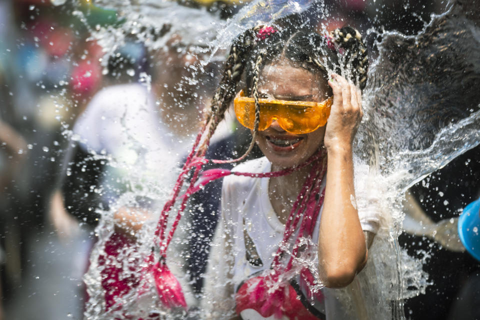 A woman reacts as a bucket of water is splashed on her during the Songkran water festival to celebrate the Thai New Year in Prachinburi Province, Thailand, Saturday April 13, 2024. It's the time of year when many Southeast Asian countries hold nationwide water festivals to beat the seasonal heat, as celebrants splash friends, family and strangers alike in often raucous celebration to mark the traditional Theravada Buddhist New Year. (AP Photo/Wason Wanichakorn)