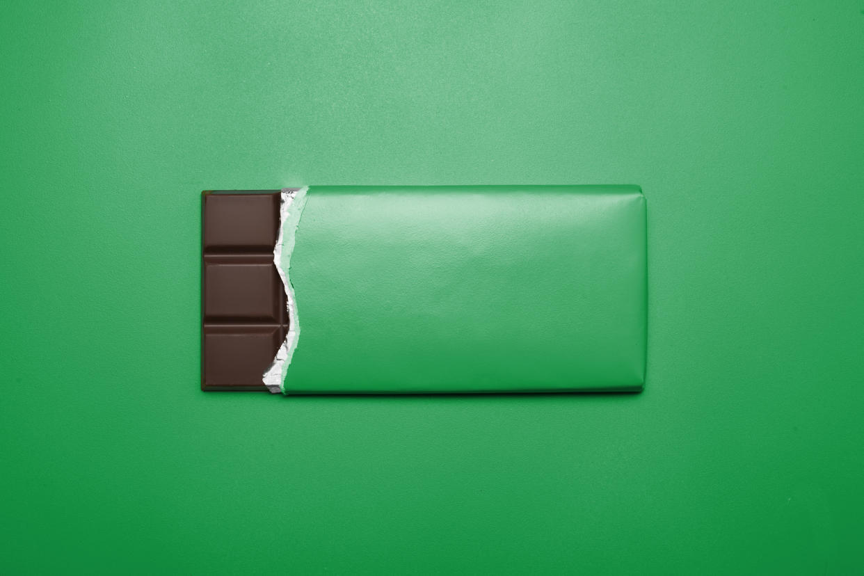 Bar of chocolate on green background