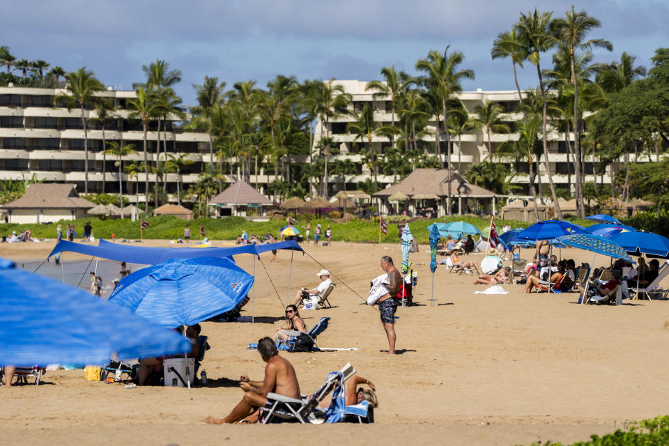 Tourists visit Kaanapali Beach, Wednesday, Dec. 6, 2023, in Lahaina, Hawaii. Residents and survivors still dealing with the aftermath of the August wildfires in Lahaina have mixed feelings as tourists begin to return to the west side of Maui. (AP Photo/Lindsey Wasson)