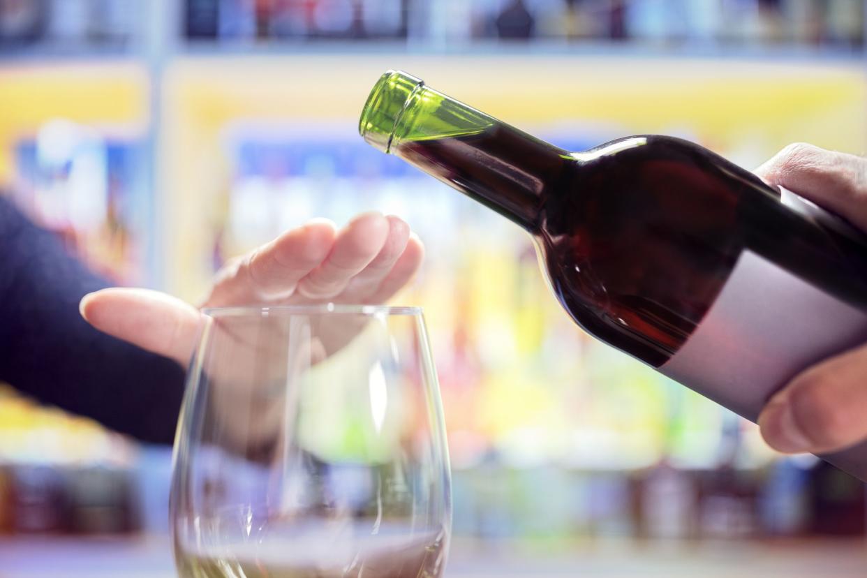 Womans hand rejecting more alcohol from wine bottle in bar