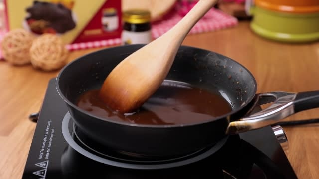 Stirring gravy in a frying pan with wooden spatula