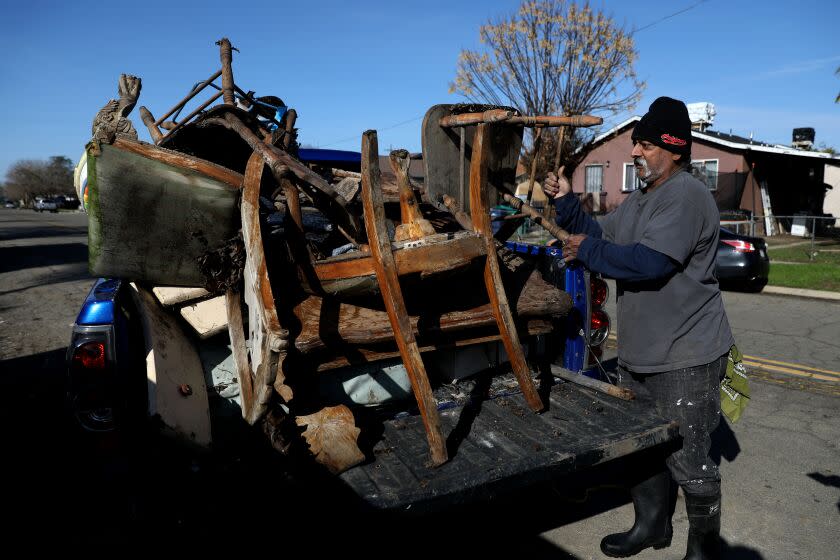 PLANADA, CA - JANUARY 18: Joe Avina, 61, who has lived in Planada his entire life, disposes of flood damaged furniture into dumpster bins lining E Broadway on Wednesday, Jan. 18, 2023 in Planada, CA. Last week's storms led the Planada Canal and Miles Creek to overflow and flood the town of Planada. The people of Planada are making their way home after last week's storm flooded the town (KFSN-TV ABC30 News). California bracing for one final round of atmospheric river storms as officials assess damage. (Gary Coronado / Los Angeles Times)