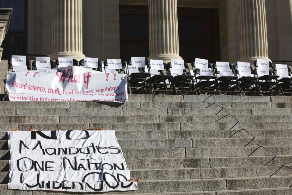 Empty chairs sit on the landing of south steps of the Kansas Statehouse during a rally against COVID-19 vaccine mandates, Saturday, Oct. 30, 2021, in Topeka, Kan. Each chair has a paper sign with the last name of a Kansas legislator. (AP Photo/John Hanna)