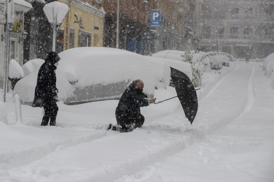 A man slips and falls crossing the street during a heavy snowfall in central Madrid, Spain, Saturday, Jan. 9, 2021, prompting a red weather alert and military assistance to rescue people trapped in cars. An unusual and persistent blizzard has blanketed large parts of Spain with snow, freezing traffic and leaving thousands trapped in cars or in train stations and airports that had suspended all services as the snow kept falling on Saturday.(AP Photo/Paul White)