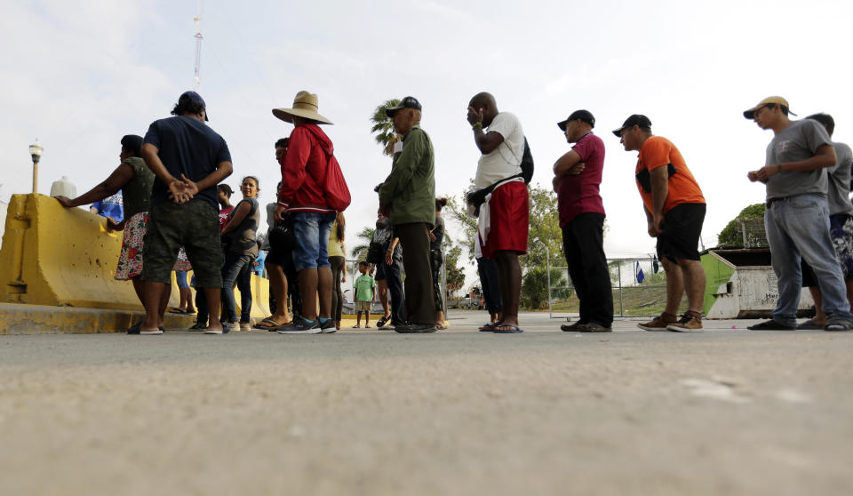 FILE - In this April 30, 2019, file photo, migrants seeking asylum in the United States line up for a meal provided by volunteers near the international bridge in Matamoros, Mexico. The U.S. government will expand its policy requiring asylum seekers to wait outside the country in one of Mexico's most dangerous cities. According to officials for two congressional Democrats, the Department of Homeland Security says it will implement its "Migrant Protection Protocols" in Brownsville, Texas, across the border from Matamoros, Mexico. Matamoros is in Mexico's Tamaulipas state, which the U.S. government warns citizens not to visit due to violence and kidnappings. (AP Photo/Eric Gay, File)