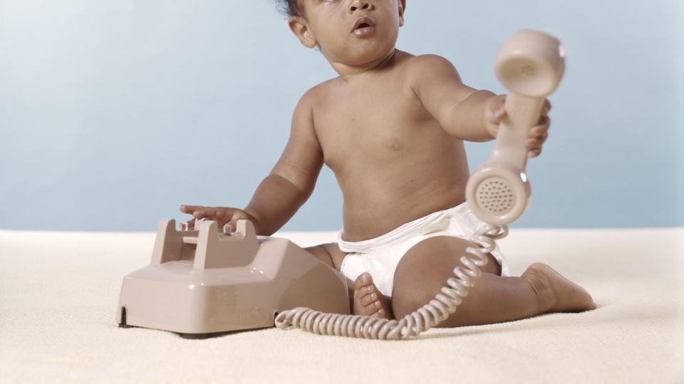 african american baby in diaper holding telephone