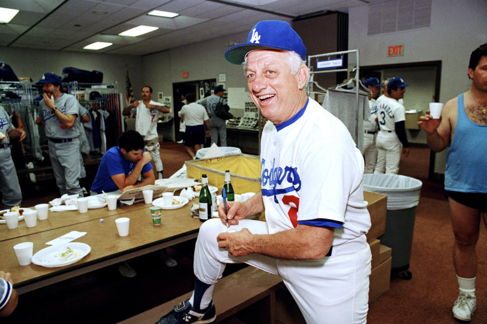 FILE - Los Angeles Dodgers manager Tommy Lasorda autographs a baseball in the Dodgertown locker-room in Vero Beach, Fla., in this Wednesday, Feb. 15, 1990, file photo. Tommy Lasorda, the fiery Hall of Fame manager who guided the Los Angeles Dodgers to two World Series titles and later became an ambassador for the sport he loved during his 71 years with the franchise, has died. He was 93. The Dodgers said Friday, Jan. 8, 2021, that he had a heart attack at his home in Fullerton, California. Resuscitation attempts were made on the way to a hospital, where he was pronounced dead shortly before 11 p.m. Thursday. (AP Photo/Richard Drew, File)