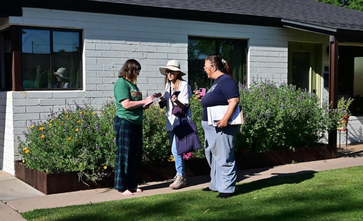 PHOTO: Volunteer canvassers Liz Grumbach  and Patricia Jones meet Lucy Meyer who signs a petition outside her home in Phoenix, Arizona on April 13, 2024. (Frederic J. Brown/AFP via Getty Images)