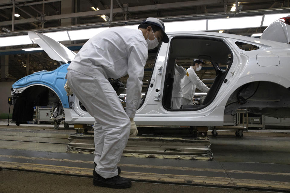 In this April 8, 2020, photo, employees work on a car assembly line at the Dongfeng Honda Automobile Co., Ltd factory in Wuhan in central China's Hubei province. The United States, Japan and France are prodding their companies to rely less on China to make the world’s smartphones, drugs and other products. But even after the coronavirus derailed global trade, few are willing to give up access to its skilled workers, vast market and efficient suppliers by moving factories closer to home. (AP Photo/Ng Han Guan)