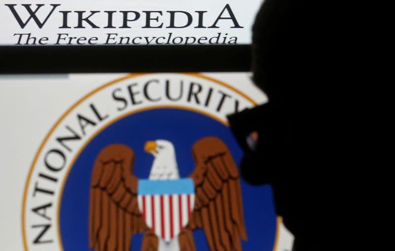 FILE PHOTO: A man is silhouetted near logos of the U.S. National Security Agency (NSA) and Wikipedia in this photo illustration taken in Sarajevo