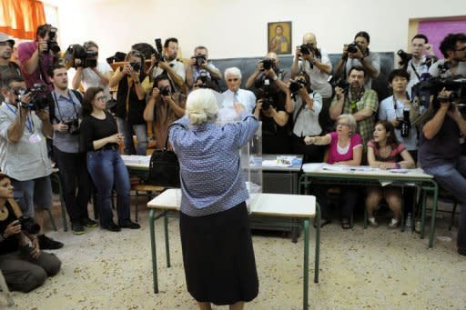 Media take pictures of an elderly woman casting her vote at a polling station in Athens. Greeks angered by austerity took to the polls on Sunday for an election that could decide their future in the euro amid unprecedented external pressure not to vote for a radical leftist party