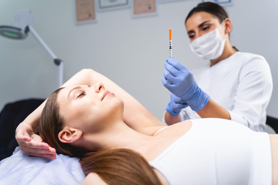 Female patient lying with her arm raised on a couch before injection from nurse