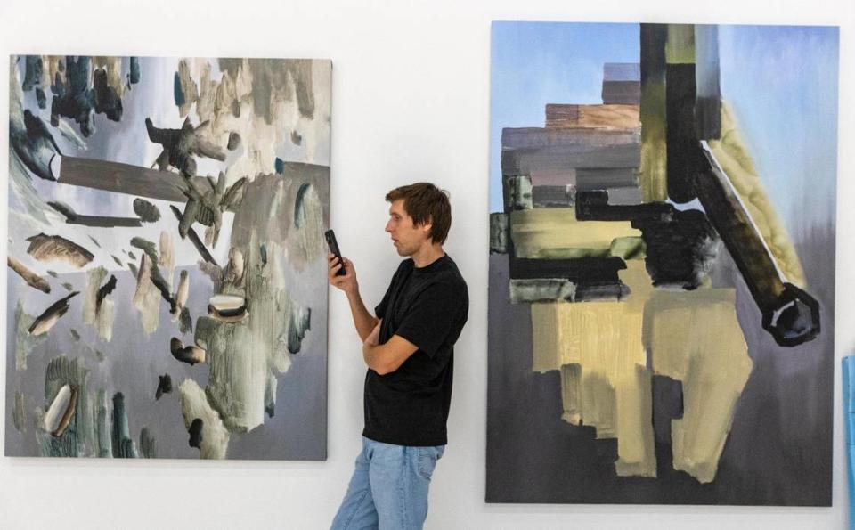 Max Voloshyn on the phone between two newly hung works inside the Voloshyn Gallery.